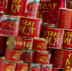 A stack of Tasty Tom tins full of tomato paste, 推荐买球平台还生产意大利面, 饼干, yoghurt drinks and edible oils for 非洲n markets.